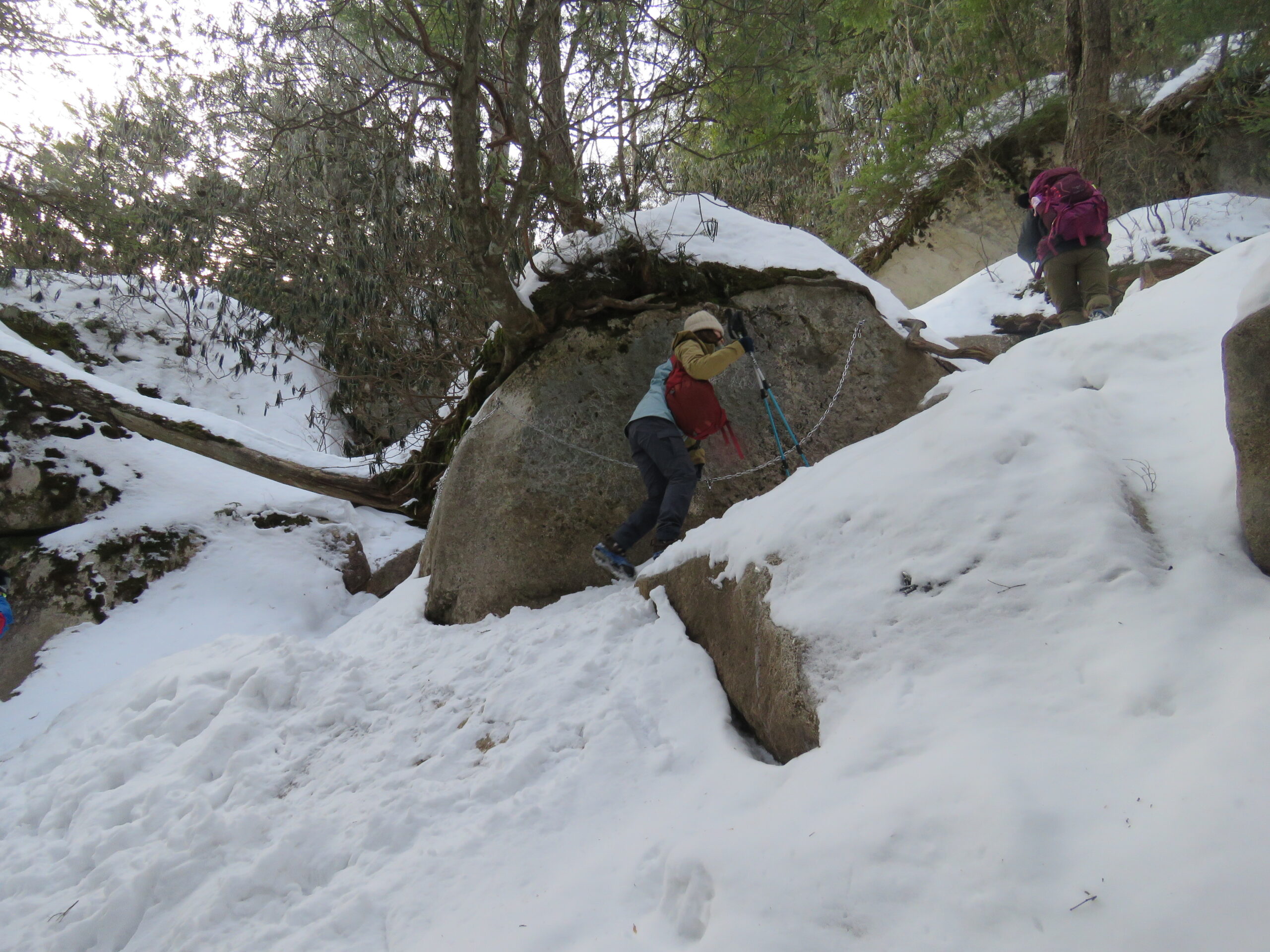 雪に覆われた花崗岩の巨岩群と登山者
