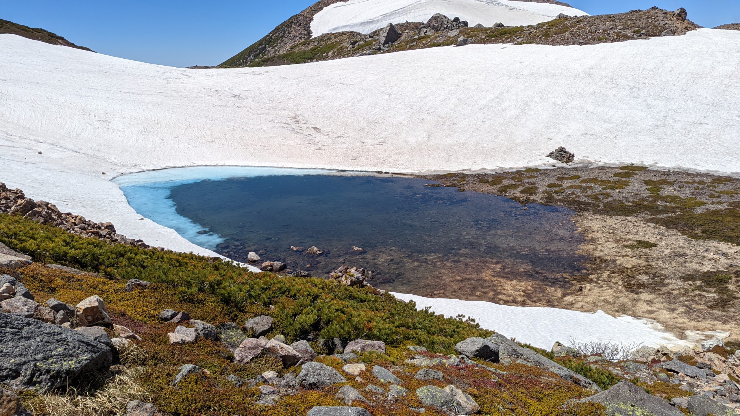白山の火口湖。雪解け水と周囲の岩が織りなす青みがかった池