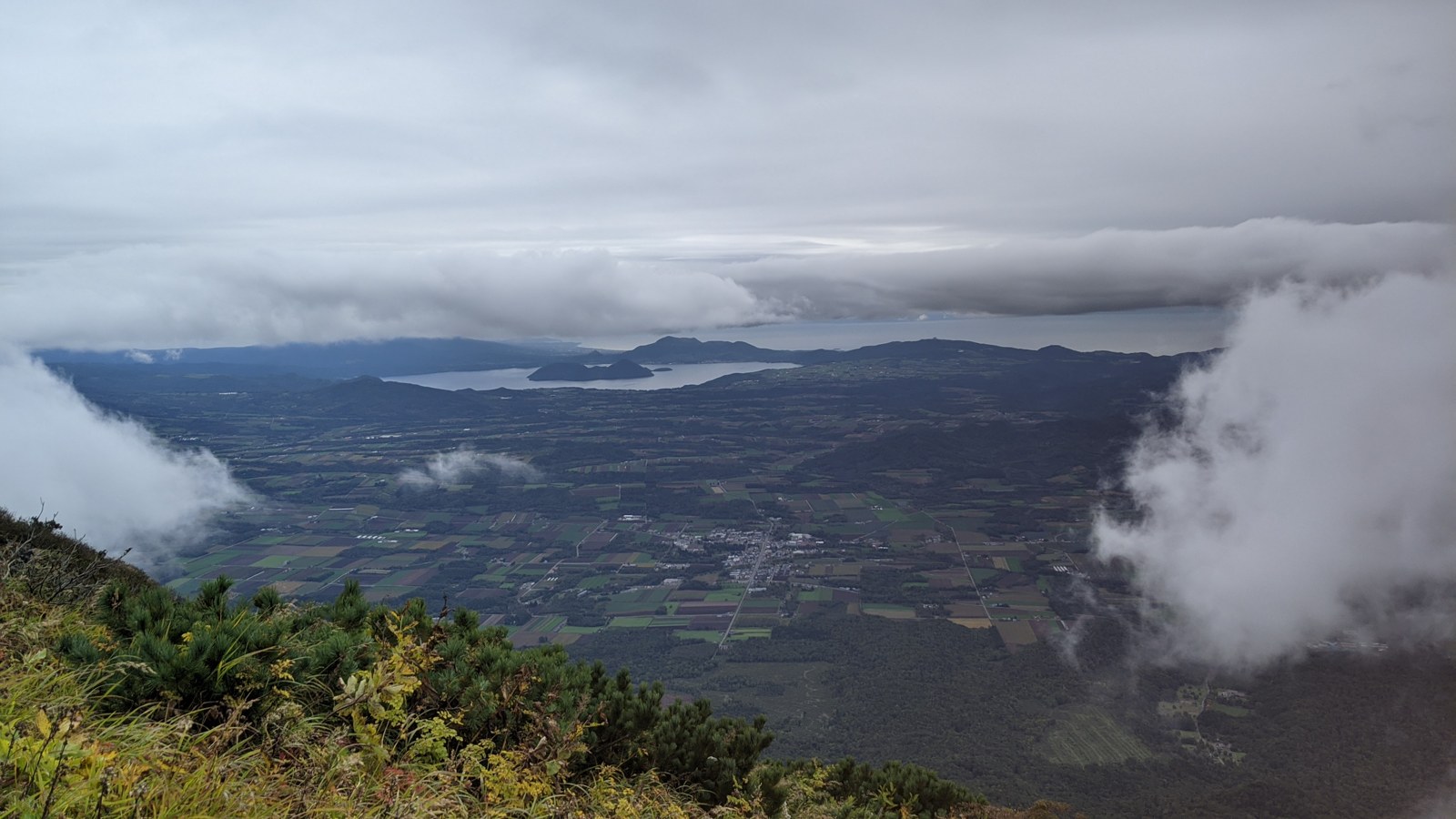 羊蹄山の山頂から洞爺湖と北海道の平野を見下ろす風景