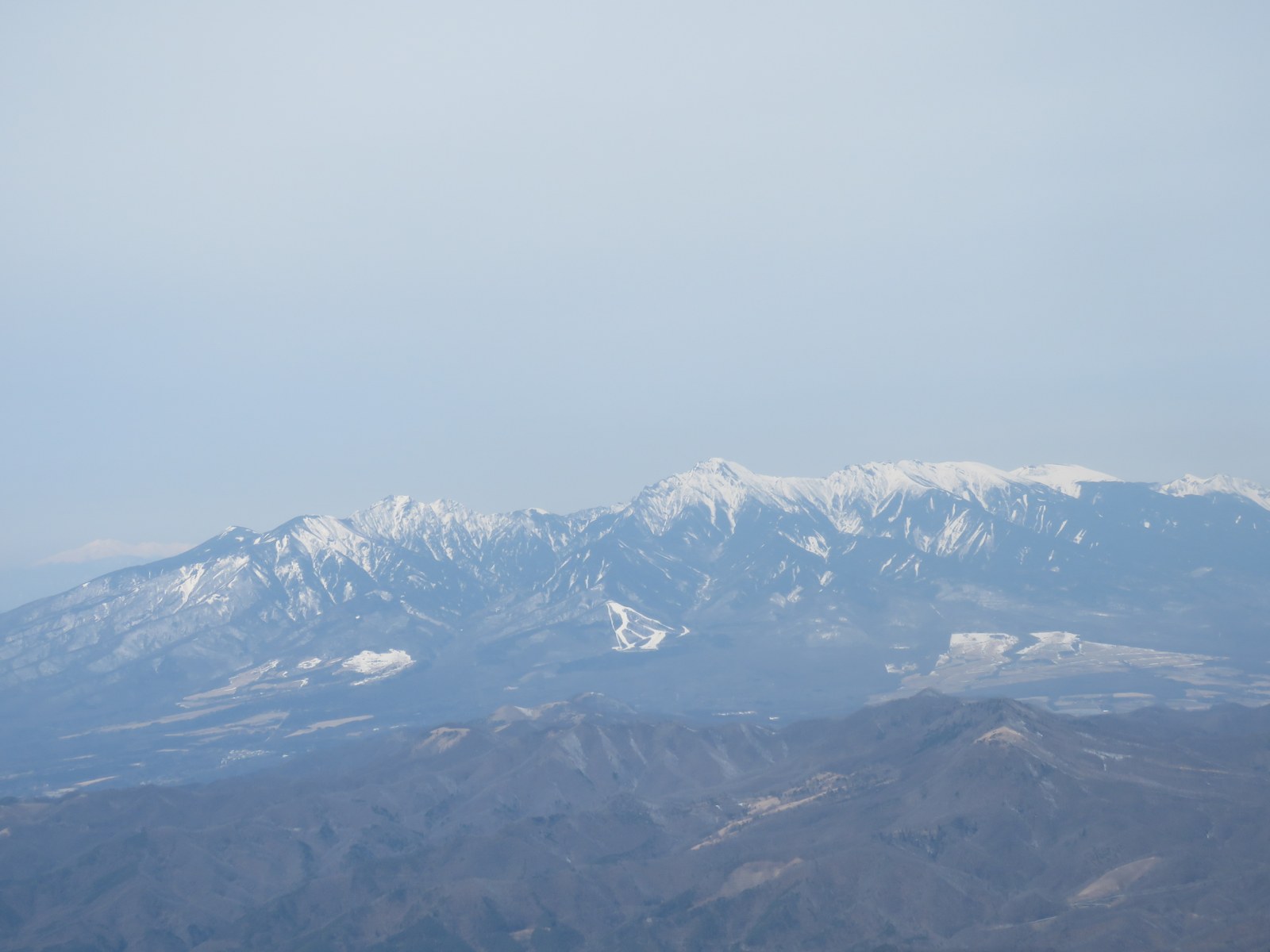 山頂から見下ろした盆地の街と遠くの山脈