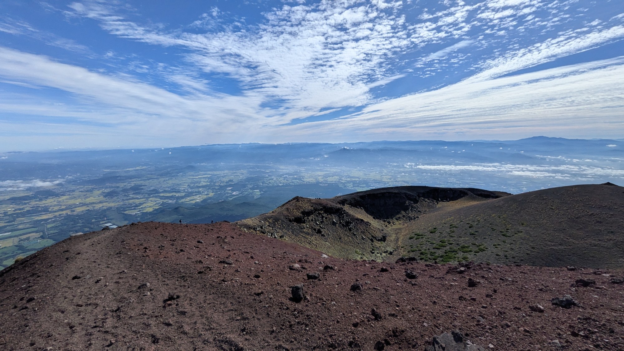 岩手山の山頂付近から見た赤い火山礫の斜面と御鉢の外輪山、眼下に広がる岩手の平野