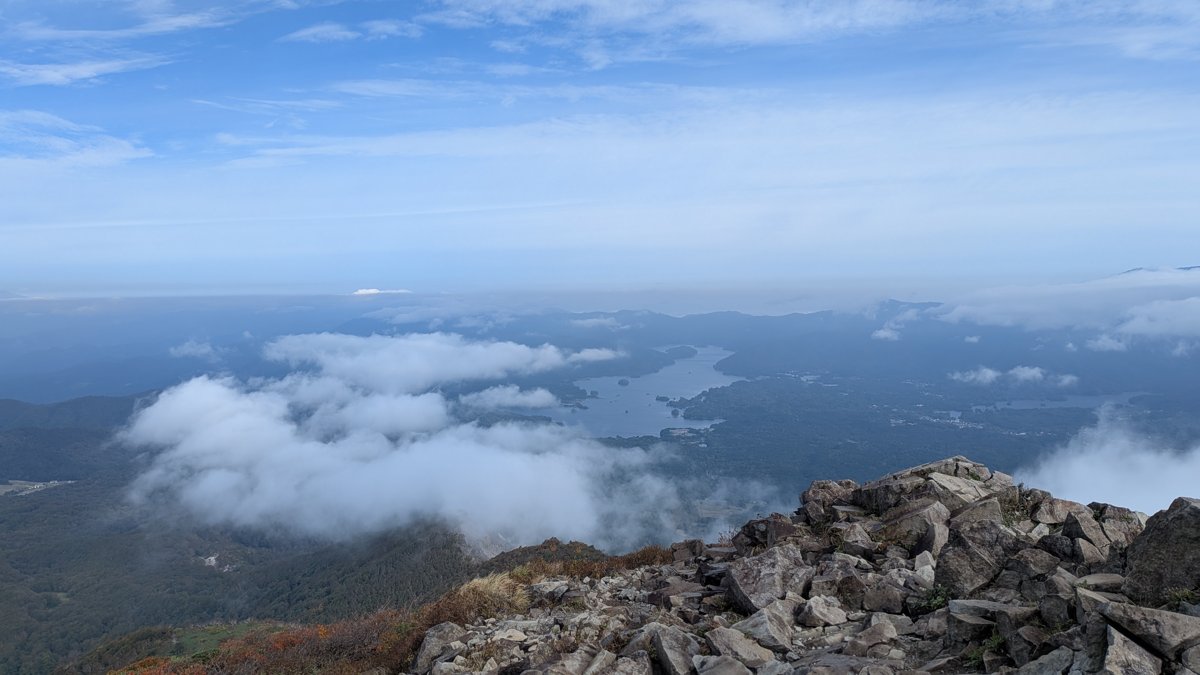 磐梯山の山頂付近から北を見下ろした景色。雲の切れ間に島の多い檜原湖が見える